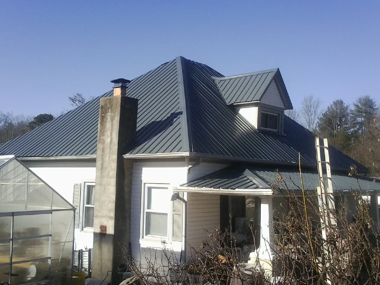 Dark blue standing seam metal roof on a white farmhouse with dormer — Slate & Tile Roof Repair by Roofing Brothers in Shokan