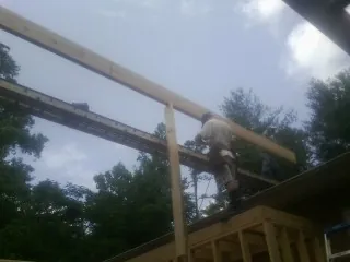 Carpenter setting a ridge beam over a new addition frame — Ice Dam Removal by Roofing Brothers in Shokan
