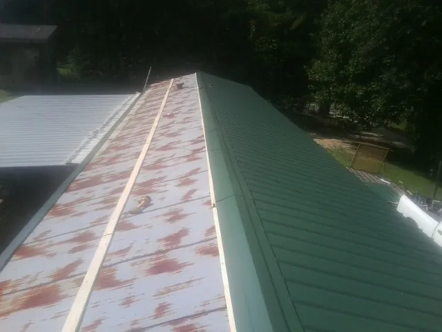 Old rusted panels beside newly installed green metal roofing — Wind Damage Roof Repair by Roofing Brothers in Shokan