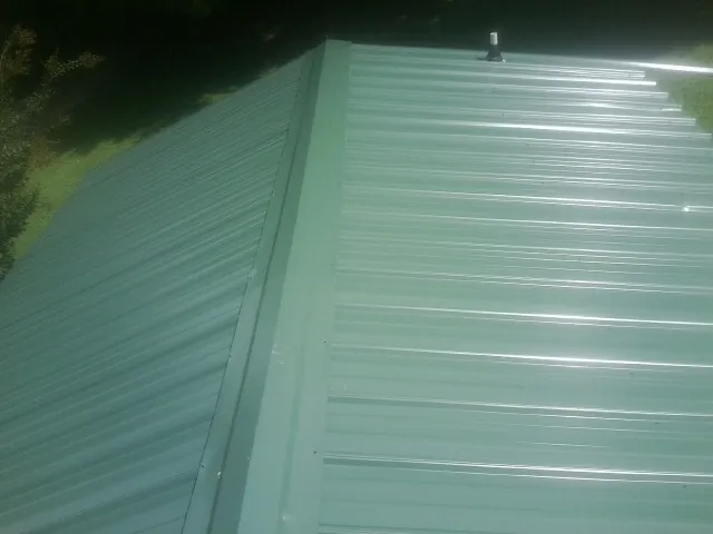 New green metal panels meeting at the ridge of a roof — Flat Roof Repair work by our crew in Shokan