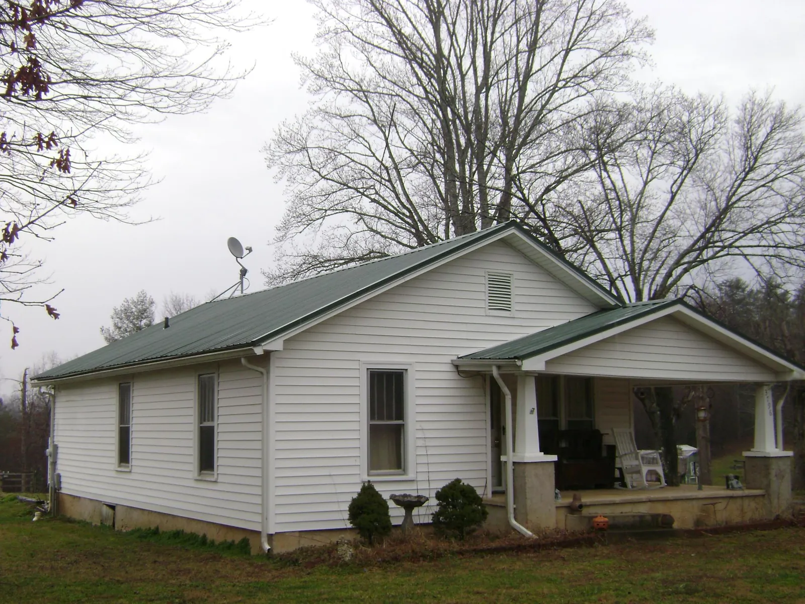 Green metal roof on a white bungalow with a side porch in Shokan