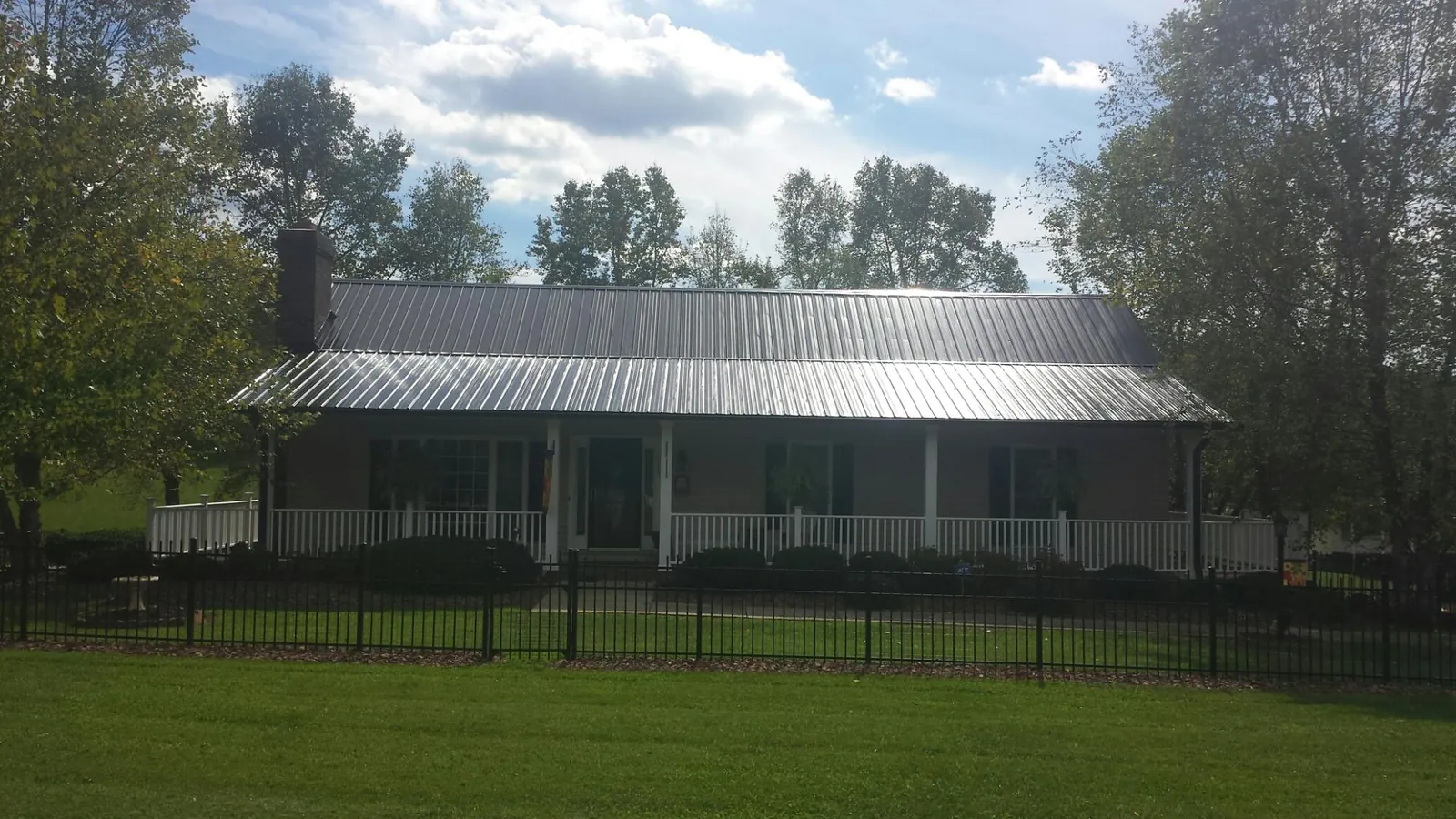 Gray metal roof on a brick ranch with a full width front porch — Gutter Guard Installation work by our crew in Shokan