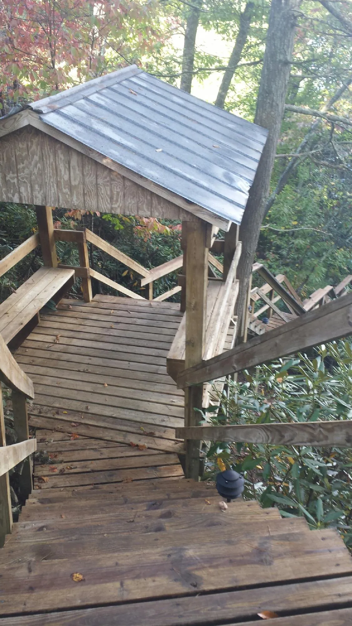 Metal roofed shelter over wooden steps on a wooded walkway — Skylight Repair & Installation work by our crew in Shokan