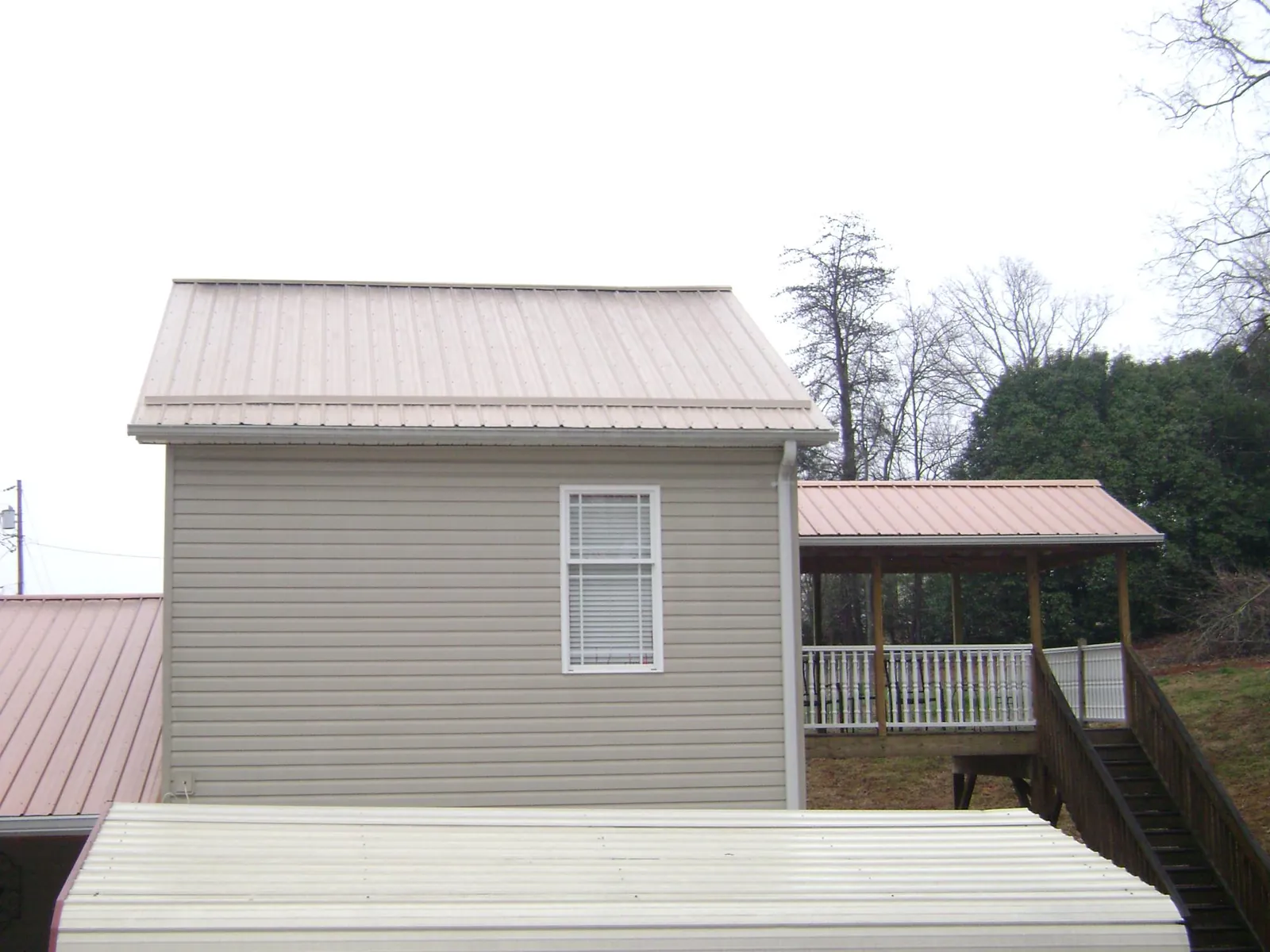 Tan metal roofs on a two story addition and attached porch, from a Roof Replacement job in Shokan