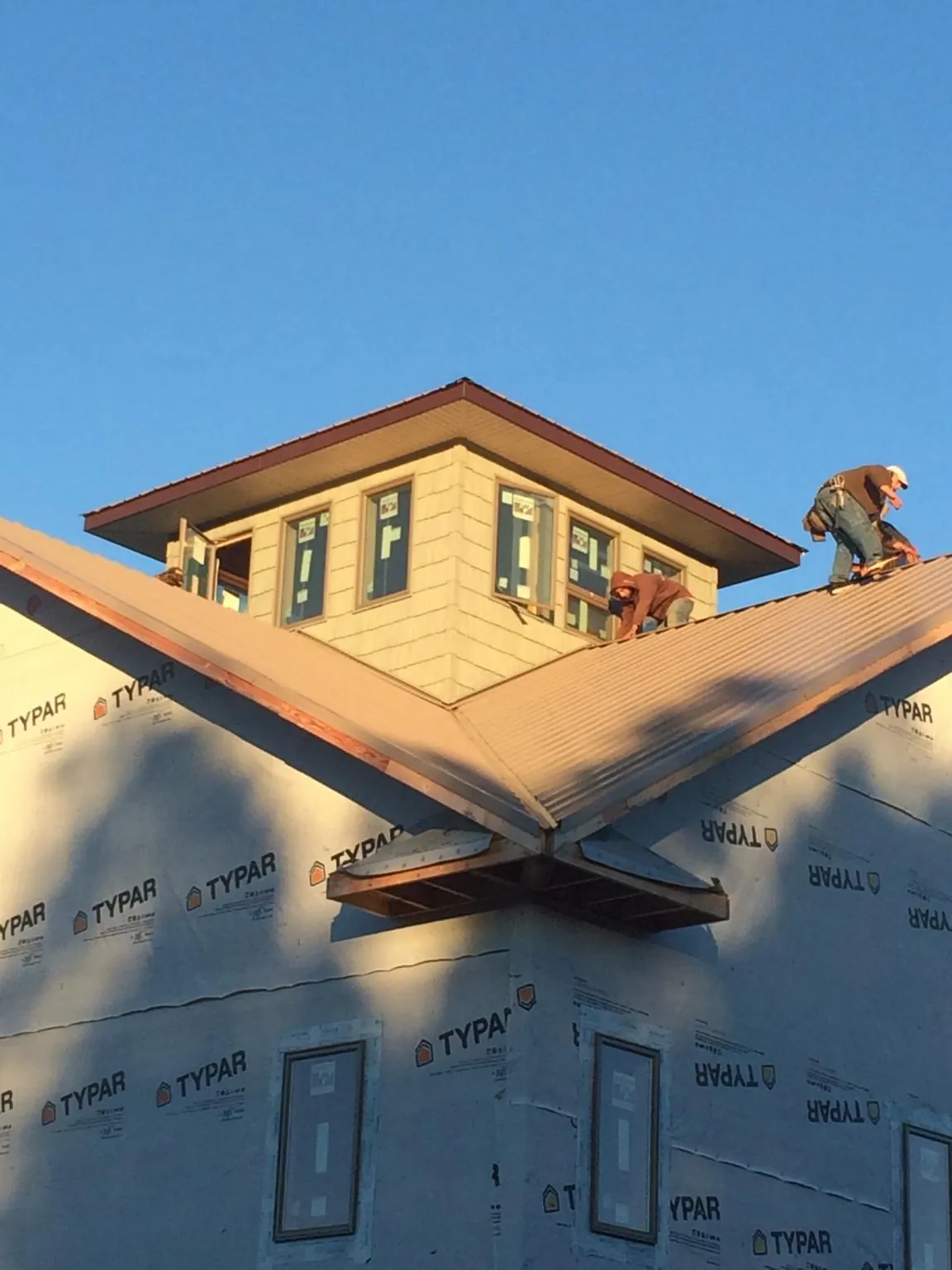 Roofers working around a rooftop cupola on a new metal roof at sunset — Roof Waterproofing in Shokan by Roofing Brothers